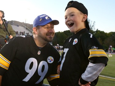 Joey Murray, 9, with his dad Scott, reacts after hearing that he was given a trip to the Pittsburgh Steelers from the Make-A-Wish Foundation at the start of the Western-Windsor game on Thursday October 4, 2018. Murray has battled acute lymphoblastic leukemia.  (Mike Hensen/The London Free Press)