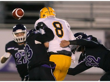 Mustangs linebacker Fraser Sopik (32) punches the ball out of the grasp of Lancers quarterback Sam Girard while safety Daniel Valente Jr. tackles during their night game at TD Stadium in London. (Mike Hensen/The London Free Press)
