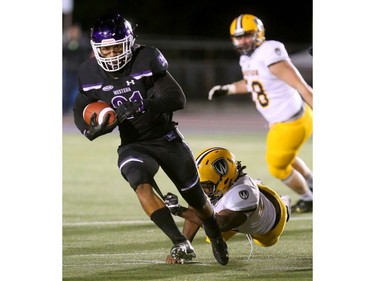 Cedric Joseph of the Mustangs runs out of the grasp of Windsor's Courtney Ellis during their night game Thursday at TD Stadium in London. (Mike Hensen/The London Free Press)