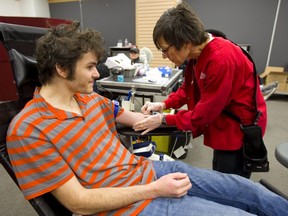 Eric Szymanczyk, of London, waits as Julie Baines, of Canadian Blood Services, puts in a needle as he donates blood at the Canadian Blood Services mobile site at CitiPlaza Mall on Friday. (MIKE HENSEN, The London Free Press)