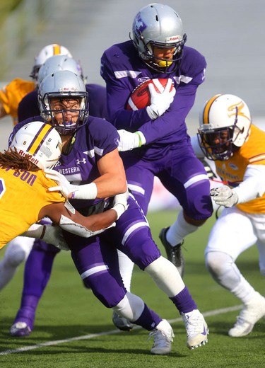 Western slotback Cole Majoros throws a block on Laurier's defensive back Malcolm Thompson to give running back Alex Taylor a bit of room in the Western Homecoming game on Saturday October 20, 2018 at TD stadium.
The Mustangs won 46-13 after a strong second half against the Golden Hawks, leaving them undefeated for the season.
Mike Hensen/The London Free Press/Postmedia Network
