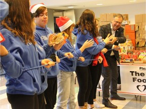 Campaign chair of the Business Cares Food Drive Wayne Dunn, right, passes along some food items to cast members of this year's Grand Theatre High School Project' while holding a rope. The exercise marked the official launch of this year's campaign and represented what a community can achieve when working together. (Jonathan Juha/The London Free Press)