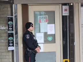 Const. Jon Dechene stands guard outside the London Relief Centre, an illegal marijuana dispensary on Richmond Street, after London police and the OPP raided the downtown shop Thursday. (DALE CARRUTHERS/The London Free Press)