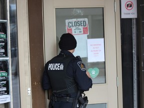 Const. Jon Dechene stands outside the London Relief Centre, an illegal marijuana dispensary on Richmond Street, after London police and the OPP raided the downtown shop on Thursday, Nov. 29, 2018. (DALE CARRUTHERS, The London Free Press)