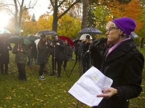 Megan Walker, the executive director of London Abused Women's Centre speaks to a crowd of umbrellas in Victoria Park. (Mike Hensen/The London Free Press)