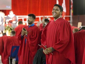 Mayur Patel flashes a graduation grin after spotting his sister Pooja in the crowd of well wishers during fall convocation ceremonies at the Agriplex in London. (Derek Ruttan/The London Free Press)
