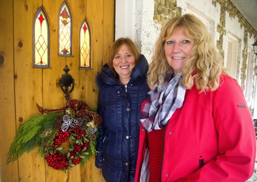 Beth Moyer and Patti Leschied are the founders of the Christmas Home Tour sponsored by Kilworth United Church. They are at the front door of the stone cottage home of Andrew Mitchell near Kilworth decorated by Parkway Gardens.  (Mike Hensen/The London Free Press)