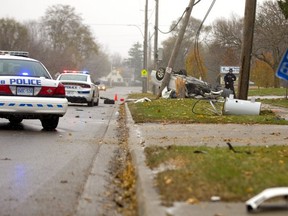 A white BMW sedan sits under the second utility post it wiped out on Brydges Street on Thursday.  The male driver of the car was unhurt after mounting the curb by a bus stop (thankfully empty) then breaking one pole, hitting some electrical boxes and then striking a second pole, leaving its front wheel and suspension sitting on the road.  Mike Hensen/The London Free Press/Postmedia Network