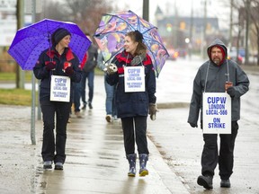 Striking Canada Post workers Amber Gall, left, Molly Nicolson Fawcett and Oscar Guisandes walk the picket line on Horton Street in London Monday. Strikers took over a distribution facility on Waterman Avenue, west of Wellington Road, and picketed seven other sites to protest proposed federal back-to-work legislation. (MIKE HENSEN, The London Free Press)