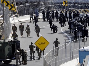 Military personnel and Customs and Border Patrol officers gather along the southbound lanes of the San Ysidro port of entry Sunday, Nov. 25, 2018, in San Diego. The Border Patrol office in San Diego said via Twitter that pedestrian crossings have been suspended at San Ysidro at both the East and West facilities. Migrants approaching the U.S. border from Mexico were enveloped with tear gas earlier Sunday after a few tried to breach the fence separating the two countries.