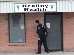 London police Const. Iain Downes leaves Healing Health, an illegal marijuana dispensary on Wonderland Road, after London police and the OPP raided the business on Thursday. (DALE CARRUTHERS, The London Free Press)