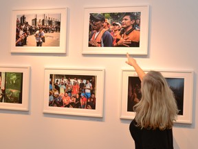Agora Gallery owner Cindy Hubert points out a group of photos shot by freelance photographer Luc Forsyth when he was covering a migrant caravan in Mexico City this spring. Galen Simmons/The Beacon Herald/Postmedia Network