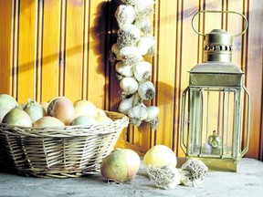 Onions on a basket, garlic braid and an oil lamp