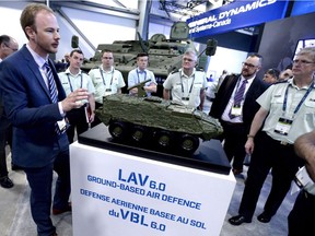 A General Dynamics LAV 6.0 is seen behind people as they gather around a scale model of a the same vehicle at the CANSEC trade show in Ottawa on Wednesday, May 30, 2018.