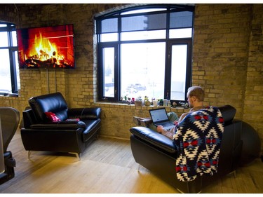 Logan Rohde of Info-Tech's research department uses the abundant window light and comfy chairs to do some work in their recently renovated building. Joel McLean founder of Info-Tech Research Group has gutted and renovated a group of old buildings on Talbot between King and York in London, Ont.  The 150 year old buildings are now a mixture of 21st century technology and bricks and beams of the original construction. Photograph taken on Wednesday December 12, 2018.  Mike Hensen/The London Free Press/Postmedia Network