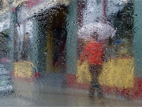 As seen through a rain dappled car window, a pedestrian walks along Richmond Row in London. (Free Press file photo)