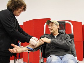 Russ Godfrey watches Canadian Blood Services donor care associate Darlene Johnson adjust the needle in his arm during a clinic at the Rotary Complex on Thursday December 27, 2018 in Stratford, Ont. (Terry Bridge/Postmedia News)