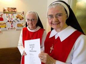 Sister Eileen Mary Walsh and Sister Carol Forhan of the Monastery of Precious Blood have a sign saying "All are Welcome Here," at their Ramsay Road location.  (Mike Hensen/The London Free Press)