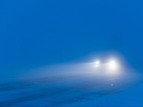 A car makes its way through a snowy street where visibility is poor./Getty Images