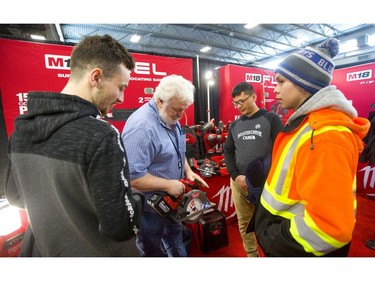Pathways teacher John Kalmbach shows students Liam Grace, left, Said Rafey and Matthew Ireland some of the new tool technology available at the Milwaukee Tools display at the Lifestyle Homeshow at the Western Fair Agriplex  in London Friday (Mike Hensen/The London Free Press)