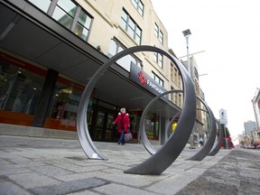 Tina Hibbard of London walks along Dundas Street in London's first section of the flex street between Richmond and Talbot  features modern loops meant to be used as bike racks in London.  (Mike Hensen/The London Free Press)
