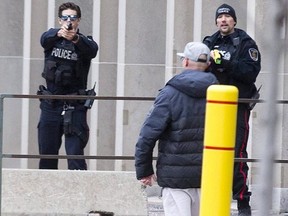 One police officer points his gun and another points his Taser at a man who was armed with a large hunting knife on Wellington Street, just north of Queens Avenue in London, Ont. on Sunday, January 6, 2019. After an hour-and-a-half, police were able to convince the man to surrender. (Derek Ruttan/The London Free Press)