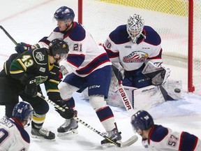 Paul Cotter of the Knights tries to deflect a puck past Saginaw goaltender Ivan Prosvetov while being checked by Hayden Davis during the first period of their game Friday night at Budweiser Gardens in London, Ont.  Photograph taken on Friday January 11, 2019.  Mike Hensen/The London Free Press/Postmedia Network