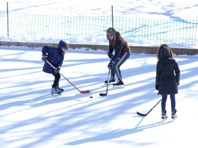 Hunter Butcher (11), Karl Wiwatowski and Joanna Suntres enjoy a game of shinny in an ice rink on the Wortley Village green space in London. (Derek Ruttan/The London Free Press)