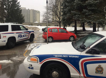 London police vehicles surround a red car at an apartment building complex on Wonderland Road north of Oxford Street following a reported home invasion in Byron. (DALE CARRUTHERS, The London Free Press)