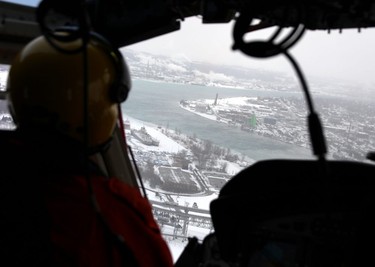 Canadian Coast Guard icebreakers rely on helicopters to see the extent of ice cover in the St. Clair River. Flight engineer Ryan Davis is pictured looking south from near the Blue Water Bridge. Tyler Kula/Sarnia Observer/Postmedia Network
