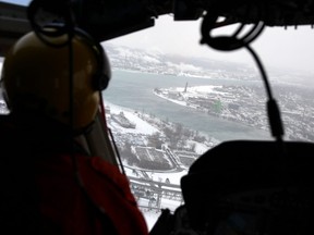 Canadian Coast Guard icebreakers rely on helicopters to see the extent of ice cover in the St. Clair River. Flight engineer Ryan Davis is pictured looking south from near the Blue Water Bridge. Tyler Kula/Postmedia Network