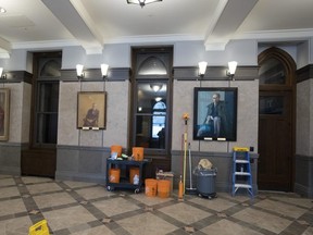 Portraits of past prime ministers John Diefenbaker, Lester B. Pearson and Pierre Elliot Trudeau hang on the walls as cleaning items stand ready in the lobby of the temporary House of Commons in preparation for the opening of Parliament . (File photo)