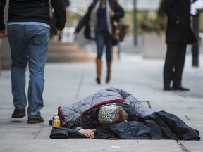 A person lies on the sidewalk on Melinda St., near Yonge and King Streets, in Toronto, Ont. on Friday January 25, 2019.