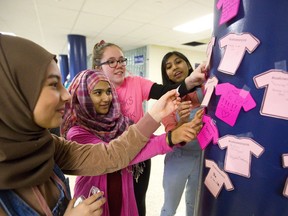 Imene Ould Noughi, 15, Maira Anser, 16, Erica Butler, 16 and Tasnia Rahman, 15 stick #OaksWearPink shirts on a pillar in the front hallway of Oakridge Secondary School on Wednesday for their anti-bullying campaign in London. The students are members of the school's social justice group and they handed out pink gum and had students sign anti-bullying shirts with their own messages. (Mike Hensen/The London Free Press)