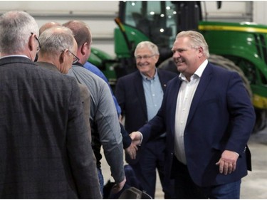 Ontario Premier Doug Ford, right, and Minister of Agriculture, Food and Rural Affairs Ernie Hardeman in the background greet local farmers at Veldale Farms Ltd. south of Woodstock on Thursday. (Greg Colgan/Postmedia Network)