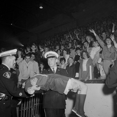 A bemused police officer carries a fan who appears to have passed out during the now-legendary Rolling Stones concert at London Gardens on April 26, 1965.