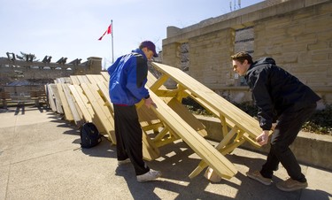 Cameron Nemes of Guelph and Nathan Durno of Vancouver pull out a picnic table on the concrete beach at Western University's community centre in London, Ont. The bright sun and mild weather brought Londoners out to embrace the spring-like temperatures. Photograph taken on Tuesday March 19, 2019.  Mike Hensen/The London Free Press/Postmedia Network
