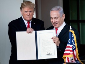 US President Donald Trump (L) and Israel's Prime Minister Benjamin Netanyahu hold up a Golan Heights proclamation outside the West Wing after a meeting in the White House March 25, 2019 in Washington, DC. - US President Donald Trump on Monday signed a proclamation recognizing Israeli sovereignty over the disputed Golan Heights, a border area seized from Syria in 1967. "This was a long time in the making," Trump said alongside Israeli Prime Minister Benjamin Netanyahu in the White House. US recognition for Israeli control over the territory breaks with decades of international consensus. (Photo by Brendan Smialowski / AFP)