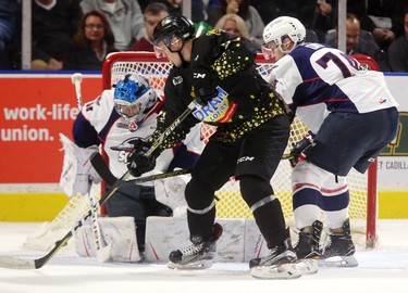Robert Thomas of the Knights tries to jam a rebound past Michael DiPietro of the Spitfires while being checked by Sean Day in the first period of their Friday night game at Budweiser Gardens.  Mike Hensen/The London Free Press/Postmedia Network (2017)