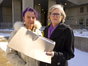 Fabienne Haller and Megan Walker of the London Abused Women's Centre stand outside the London courthouse with a file full of documents containing the named of men who have been charged with buying sex.  Photograph taken on Monday March 4, 2019.  Mike Hensen/The London Free Press/Postmedia Network