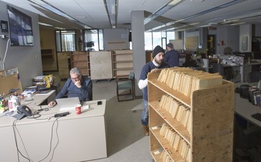 John Durston of Campbell Movers walks past journalist Norm DeBono while removing newspaper clipping and photograph files from the newsroom of the London Free Press in London, Ont. on Wednesday March 6, 2019. The files will are destined for the London Public Library. The London Free Press is moving from it's current location a 369 York Street to 210 Dundas Street. Derek Ruttan/The London Free Press/Postmedia Network