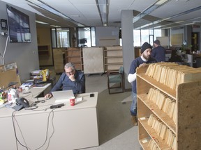 John Durston of Campbell Movers walks past journalist Norman De Bono while removing newspaper clippings and photograph files from the newsroom of The London Free Press in London, Ont. on Wednesday March 6, 2019. The archives are being donated by the newspaper to the London Public Library. The London Free Press is moving from its current location at 369 York St. to the heart of downtown, at 210 Dundas St. Derek Ruttan/The London Free Press/Postmedia Network