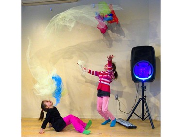 Tanaya Paris, 7 sits and watches as her twin sister, Taleya Paris, flings gossamer light fabrics into the air in the dance party room at the London Children's Museum pajama party held on Friday. They were attending the museum's first pajama party, the first of a long slate of activities the museum has planned to help parents out during March break. (Mike Hensen/The London Free Press)