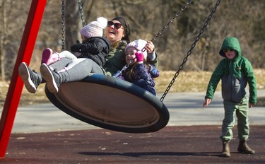 Laura Dravis laughs as she's pushed on a big swing with her daughters Ivory, 2, and Violet, 4, by Jaron Lewis, the six-year-old son of a friend. All the moms and grandmothers at Springbank Park who were polled agreed that spring has arrived in London, although not officially until Wednesday. Photograph taken on Tuesday March 19, 2019.  Mike Hensen/The London Free Press/Postmedia Network