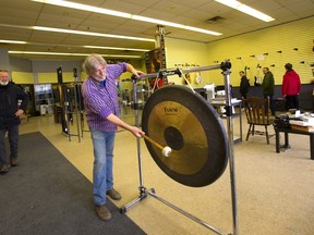 John Bellone rings his gong to open the last day of business at John Bellone Musical Instruments on Sunday. The building at 446 York St. is slated to become a supervised drug use site.  (Mike Hensen/The London Free Press)
