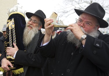 Menachem Block carries the just finished Torah scroll, in a jubilant parade from Alumni Hall at Western on Sunday, March 31, 2019 to Chabad House on Richmond Street. The scroll was dedicated to Yitzchok Block and his wife Laya, prominent members of the Jewish community in London who founded Chabad House at Western and the London Community Hebrew Day School.  Rabbi Yerachmiel Zalmanov blows a rams horn as people were dancing and singing throughout the processional. Mike Hensen/The London Free Press/Postmedia Network