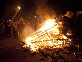 A man hurls a piece of wood on top of a TV news truck which was flipped and set alight on Fleming Drive in London in the early hours of Sunday March 18, 2012.  Riot police, along with firefighters and paramedics, stood by and observed from a distance while being targeted with bottles and other projectiles as more fuel, including sections of nearby fences and televisions, were added to the fire. CRAIG GLOVER The London Free Press / QMI AGENCY