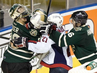 Zack McQueen of the Windsor Spitfires gets a face full of leather from London Knights goalie  Michael Houser and defenceman Scott Harrington in the third period of their OHL playoff hockey game at the John Labatt Centre in London, Ontario on Friday, March 23, 2012. DEREK RUTTAN/ The London Free Press /QMI AGENCY