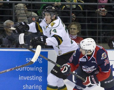 London Knights defenseman Aiden Jamieson keeps his eyes on an airborne puck near his face as Windsor Spitfires forward Sam Povorozniouk attempts to tap it with his stick during their OHL junior hockey regular season game at Budweiser Gardens in London, Ontario on Sunday December 28, 2014. Windsor won the game 5-4 in a shootout. CRAIG GLOVER/The London Free Press/QMI Agency