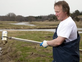 Todd Sleeper collects garbage along the banks of the Thames River near his home northwest of St. Marys in this Postmedia file photo. (The London Free Press)